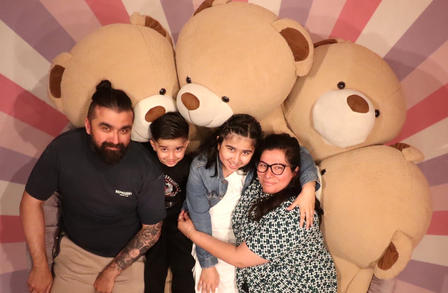 Dr. Harpreet Atwal with her husband and their two children, smiling together among giant teddy bears